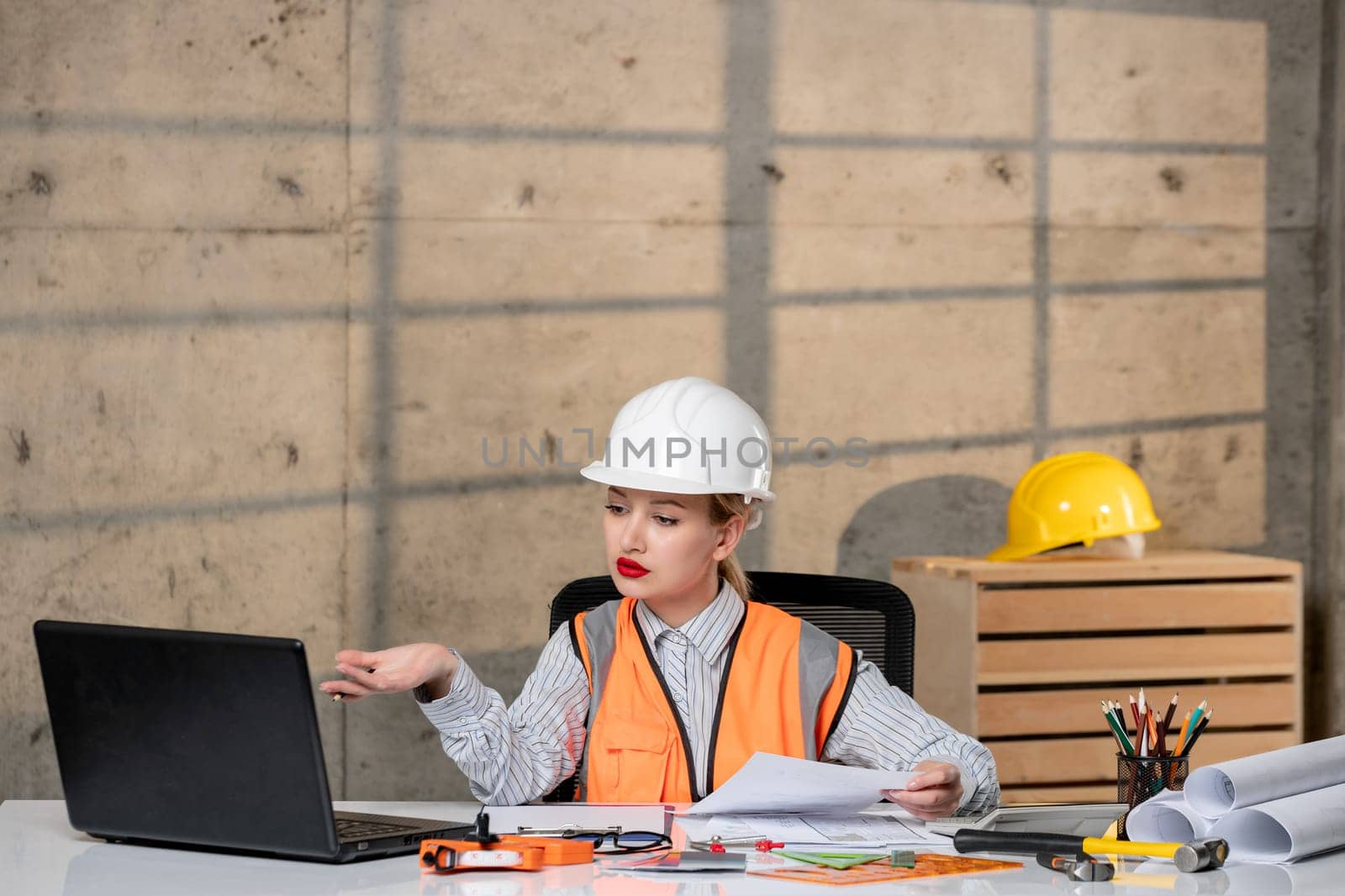engineer smart young cute blonde girl civil worker in helmet and vest concentrated by Kamran