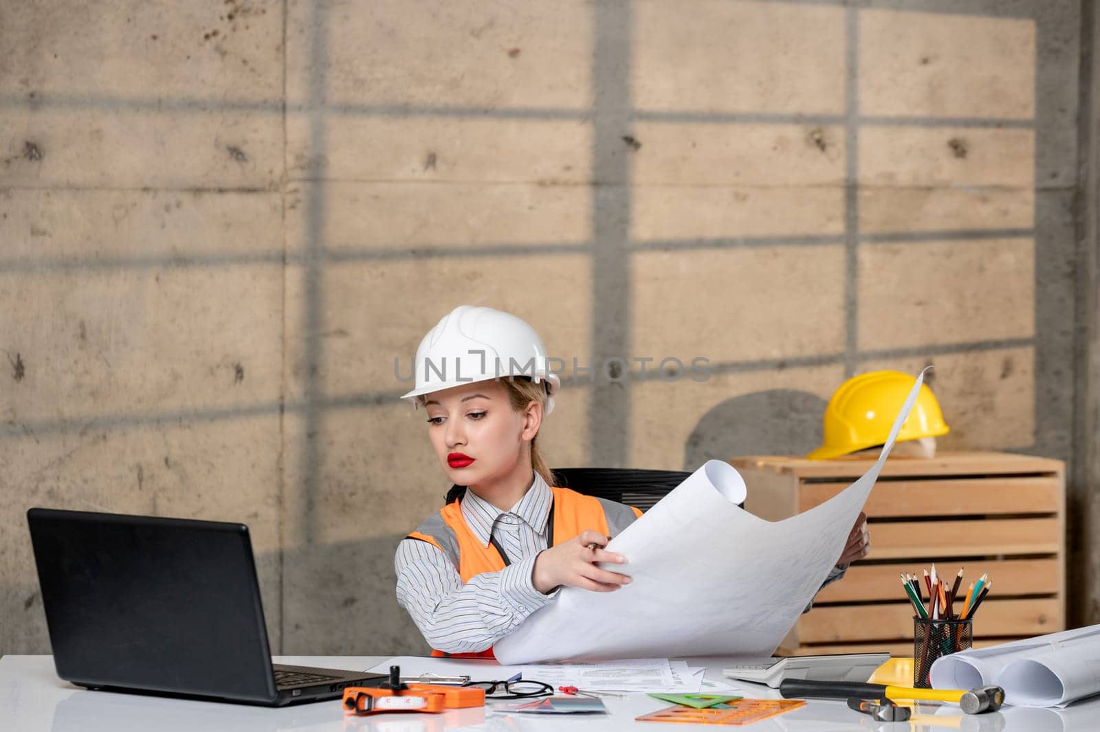 engineer smart young cute blonde girl civil worker in helmet and vest looking at project