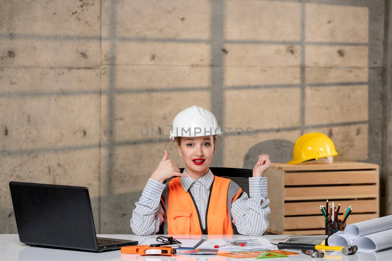 engineer smart young cute blonde girl civil worker in helmet and vest making call gesture