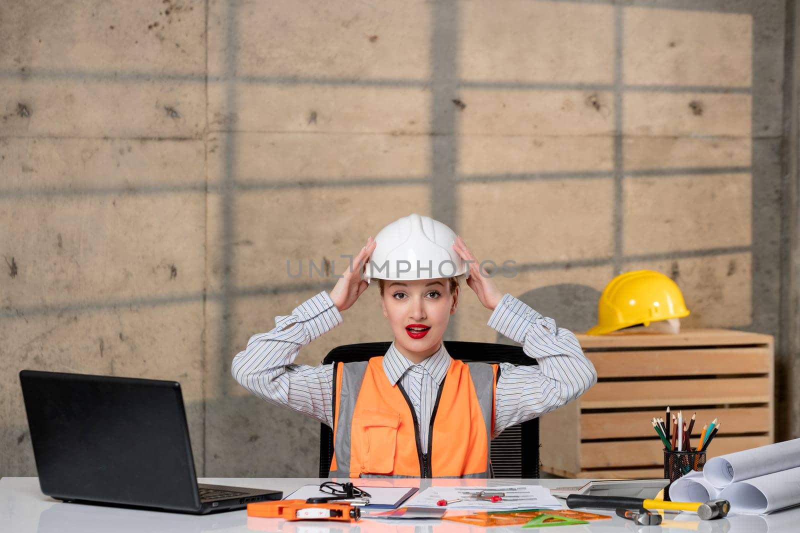 engineer smart young cute blonde girl civil worker in helmet and vest taking helmet off