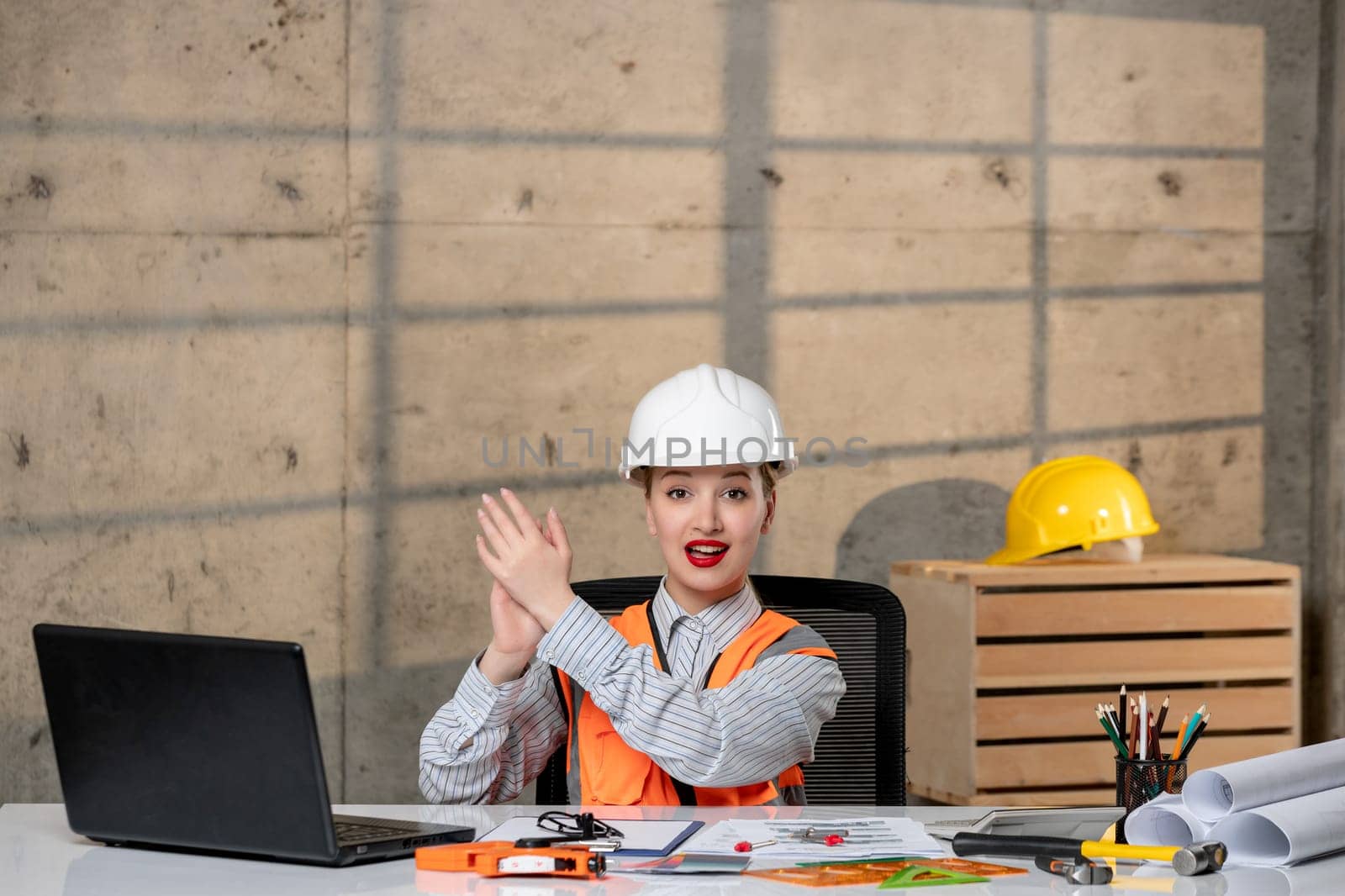 engineer young smart cute blonde girl civil worker in helmet and vest clapping hands