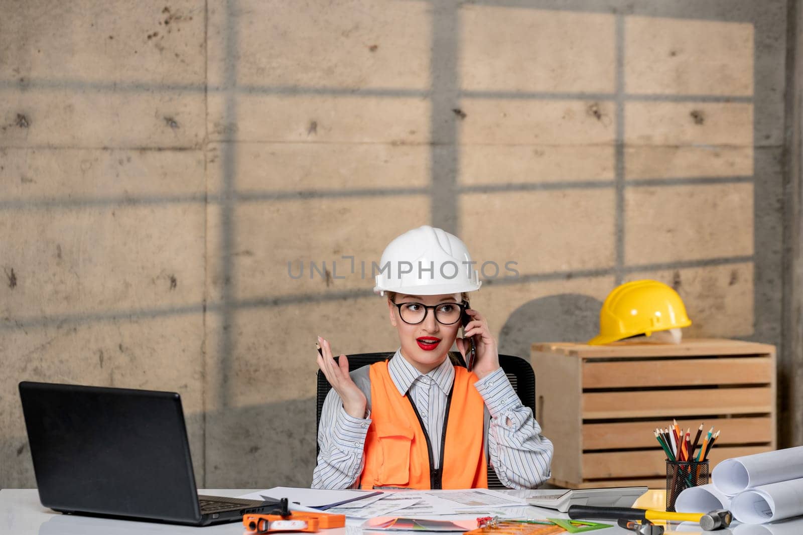 engineer in helmet and vest civil worker smart young cute blonde girl on the phone