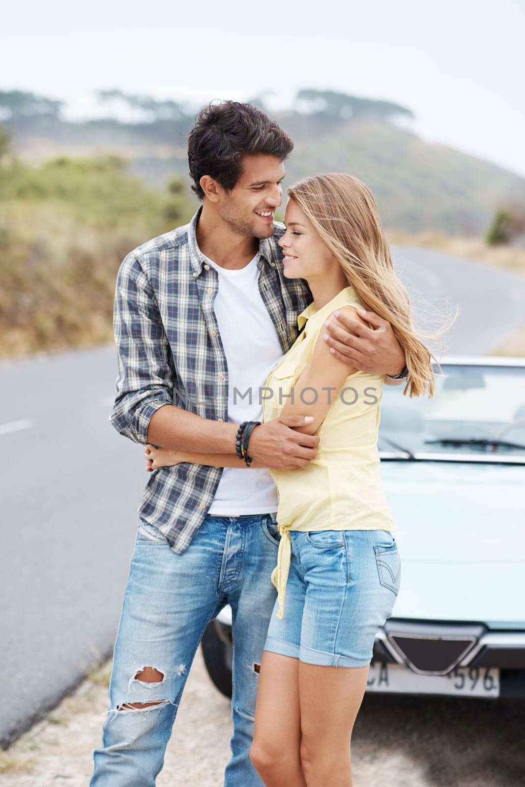 Enjoying their relationship. A romantic young couple standing alongside their convertible while on a roadtrip
