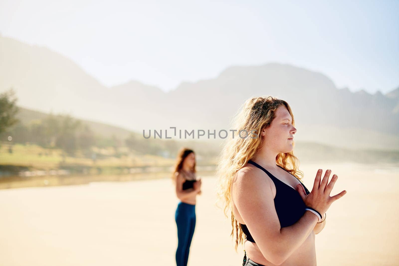 My life is a lot more peaceful with yoga in it. Defocused shot of a young woman practising yoga and the beach