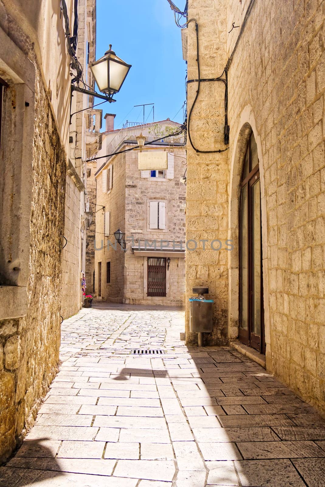 Narrow street with stone houses. Old houses and old narrow alley in Trogir, Croatia, Europe by PhotoTime
