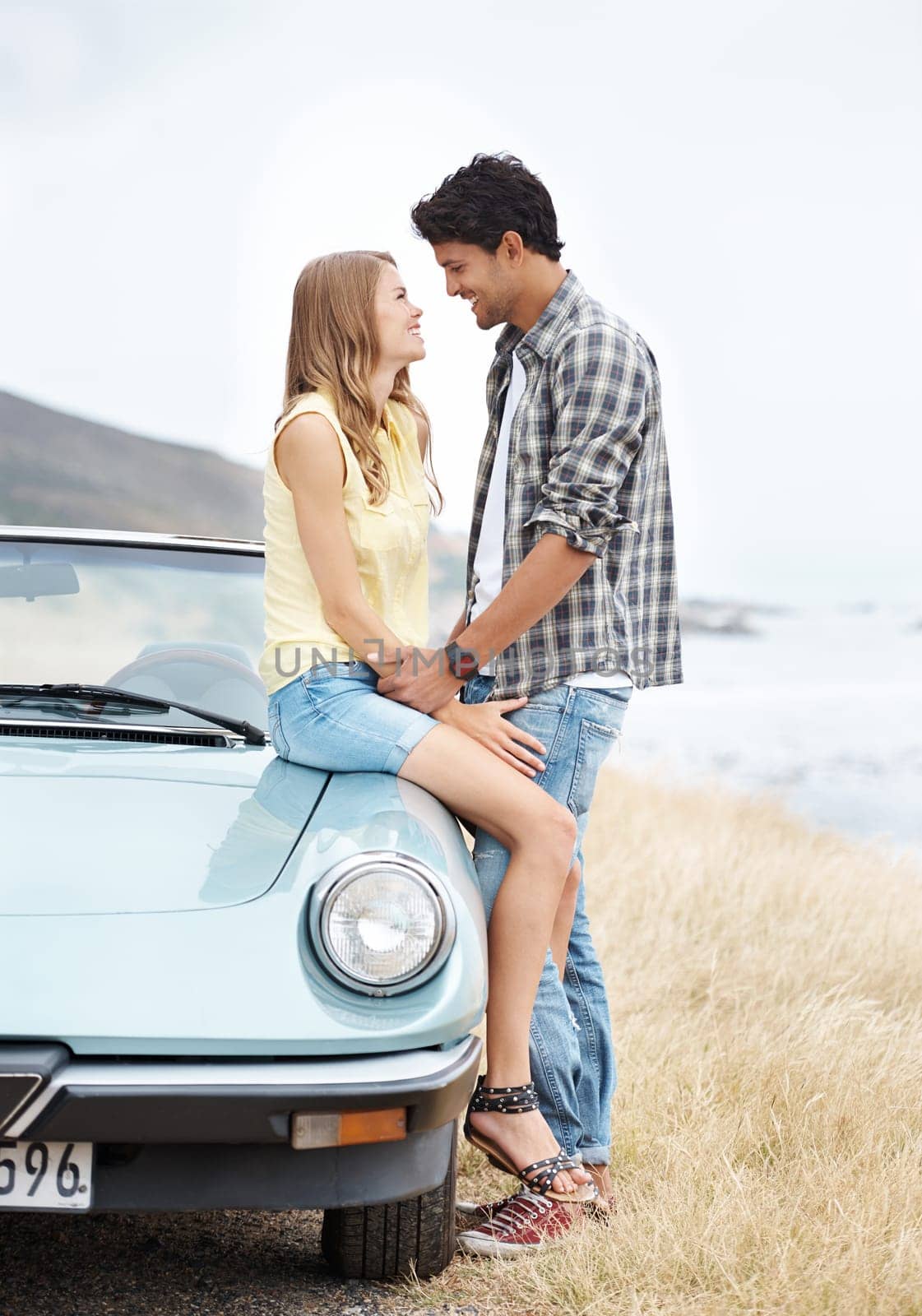 Making that special connection. A young couple sharing a romantic moment on a hilltop after taking a scenic drive. by YuriArcurs