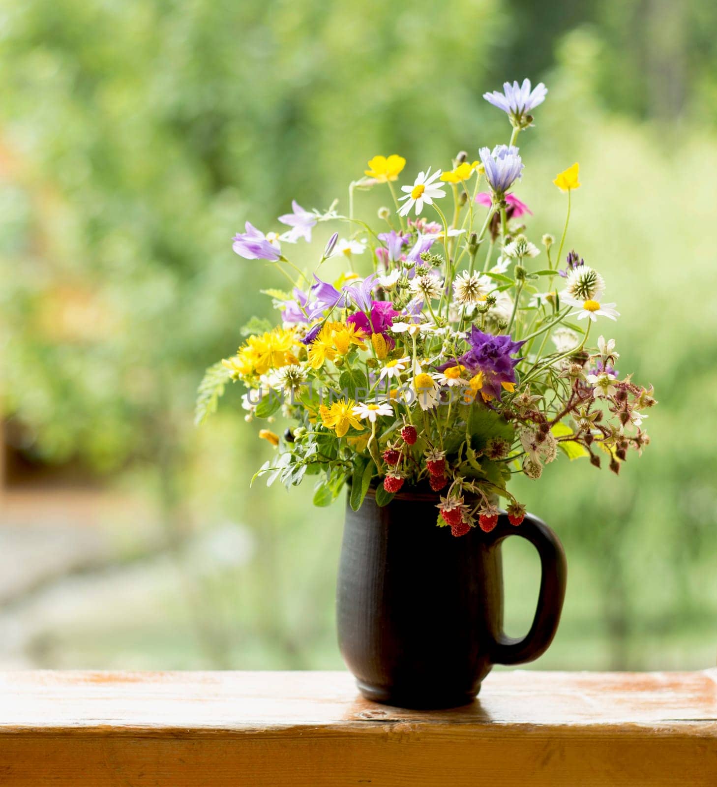 Medicinal plants. Summer beautiful bouquet of bright wildflowers with ripe strawberries on a wooden window sill by aprilphoto