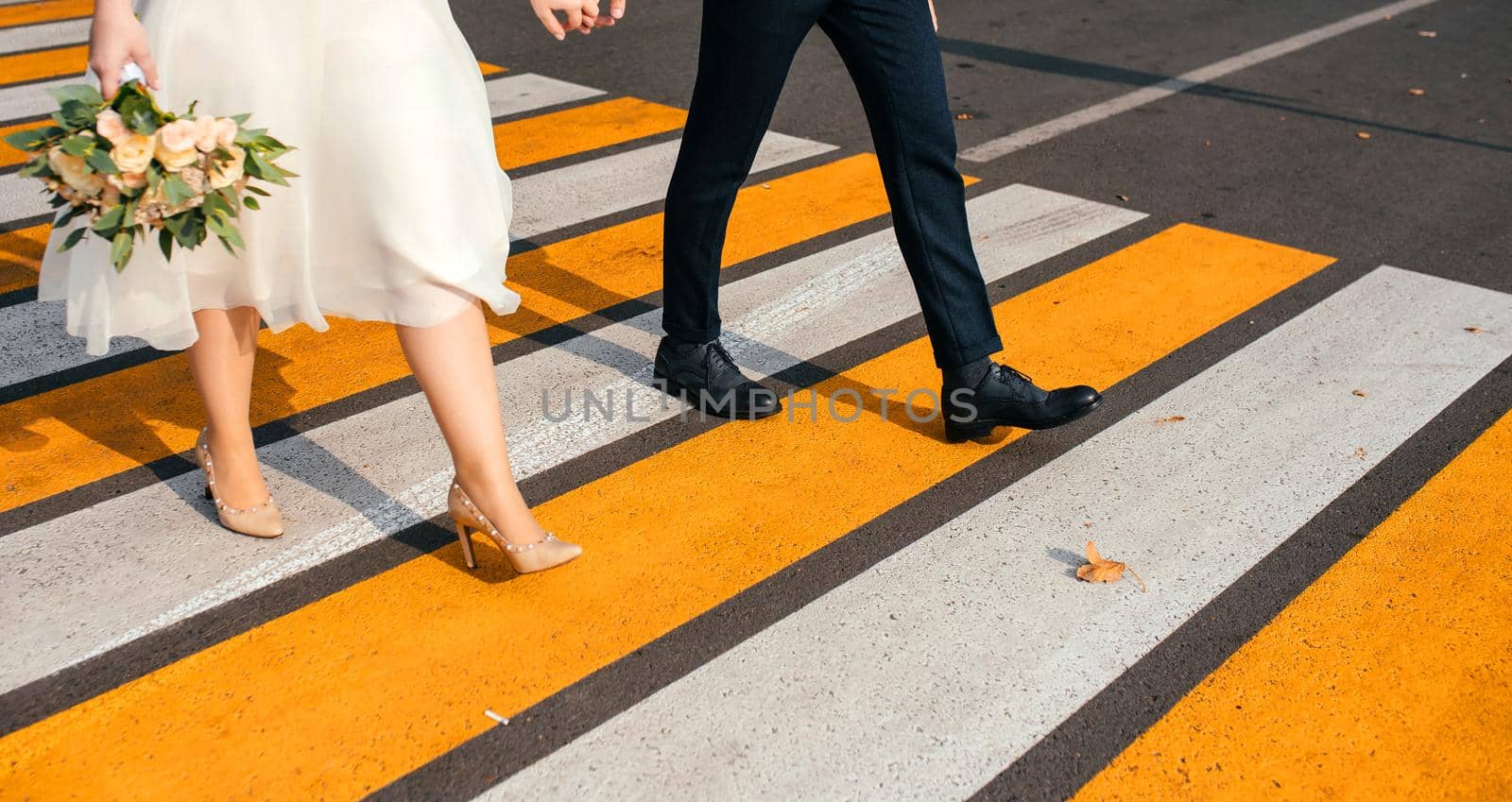 A happy couple crosses the road at a bright yellow pedestrian crossing