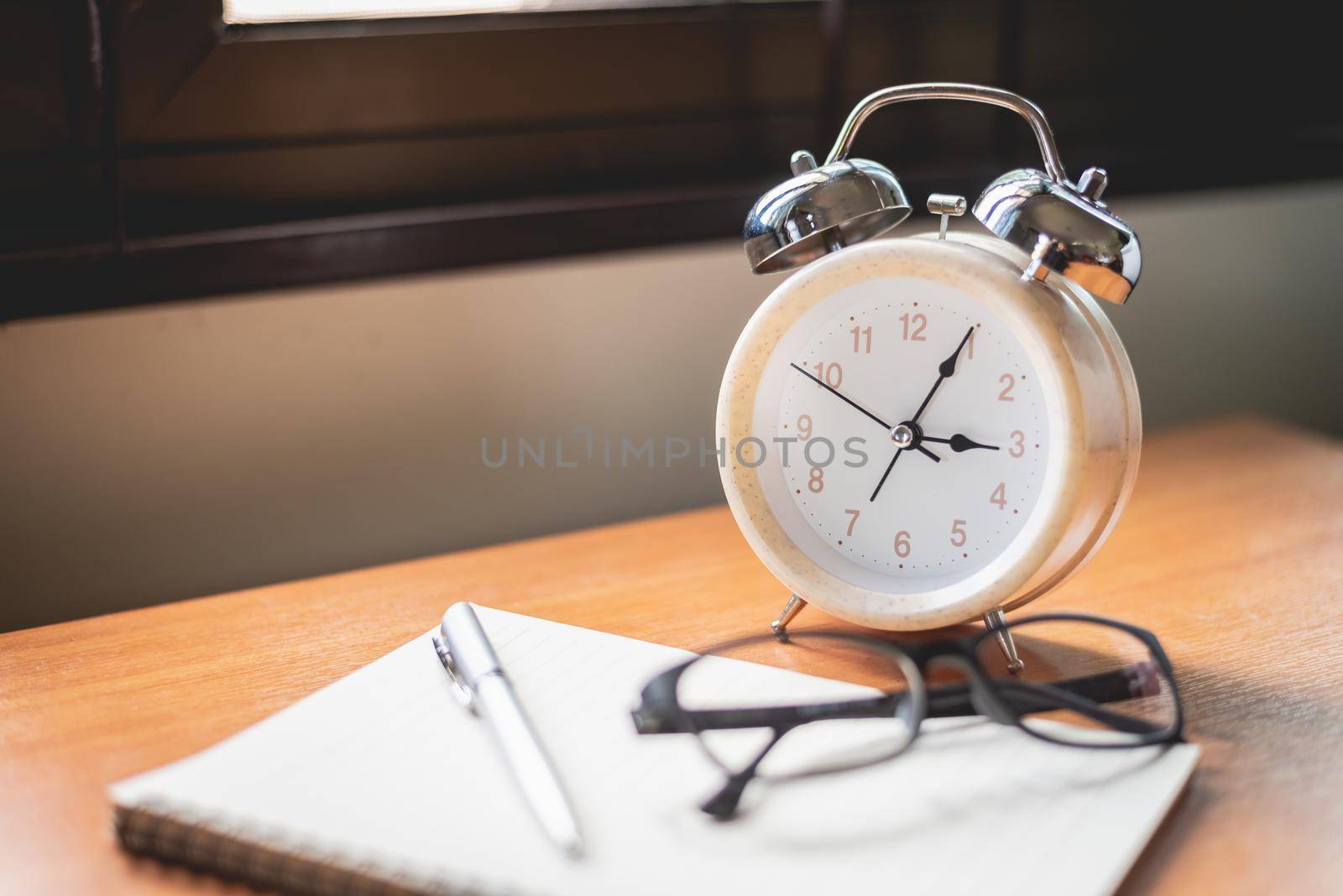 close up of glasses, clock and notebook on office table