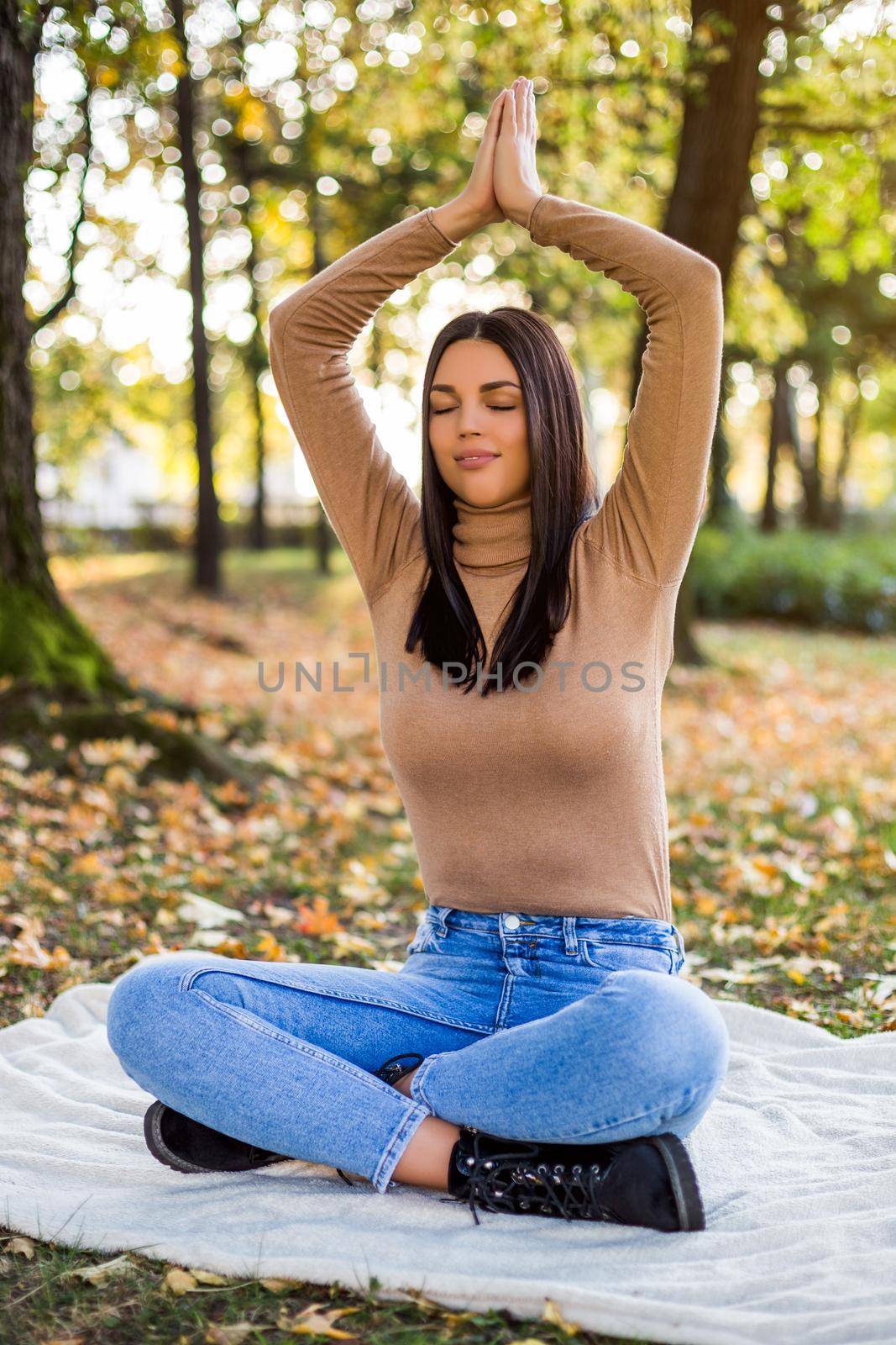 Beautiful woman meditating while resting and enjoys in autumn in the park.