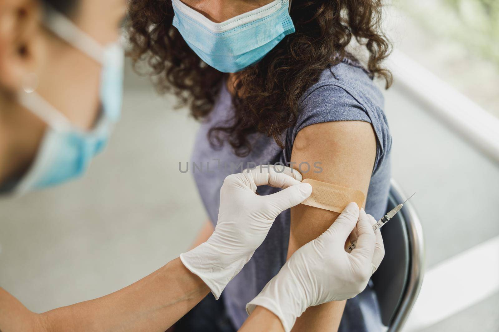 Close-up of a nurse applying a band aid to an African American girl after receiving a vaccine due to coronavirus pandemic.