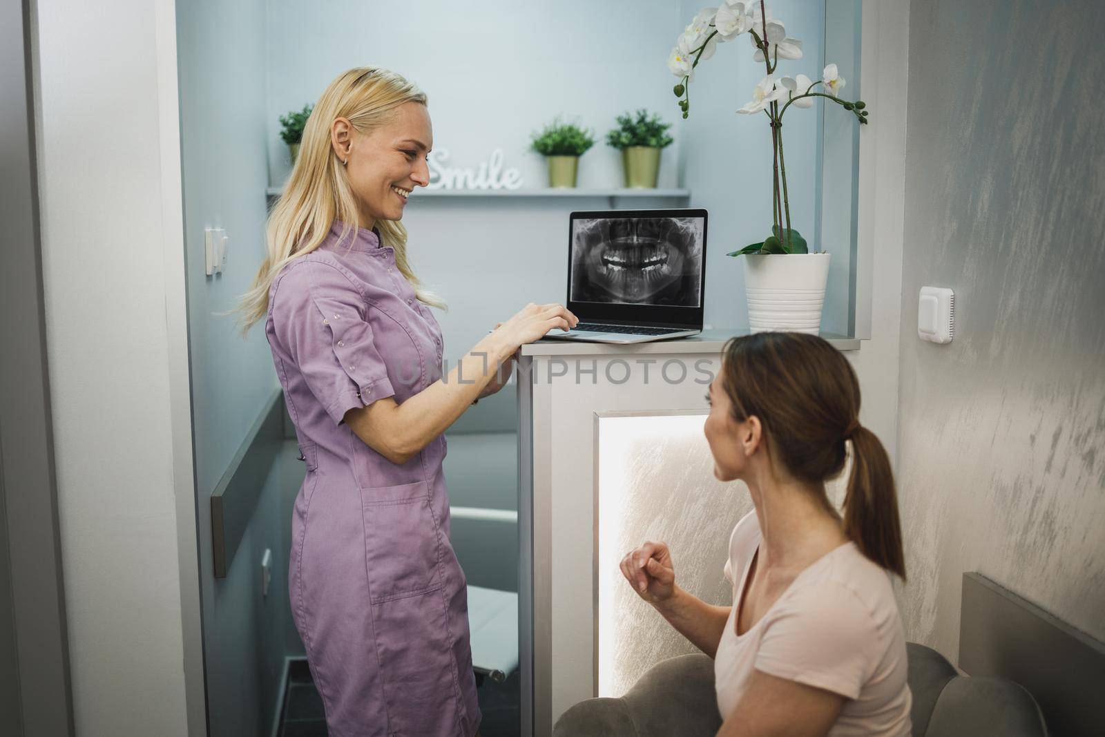 An attractive young woman sitting in waiting room and having a consultation with her dentist.