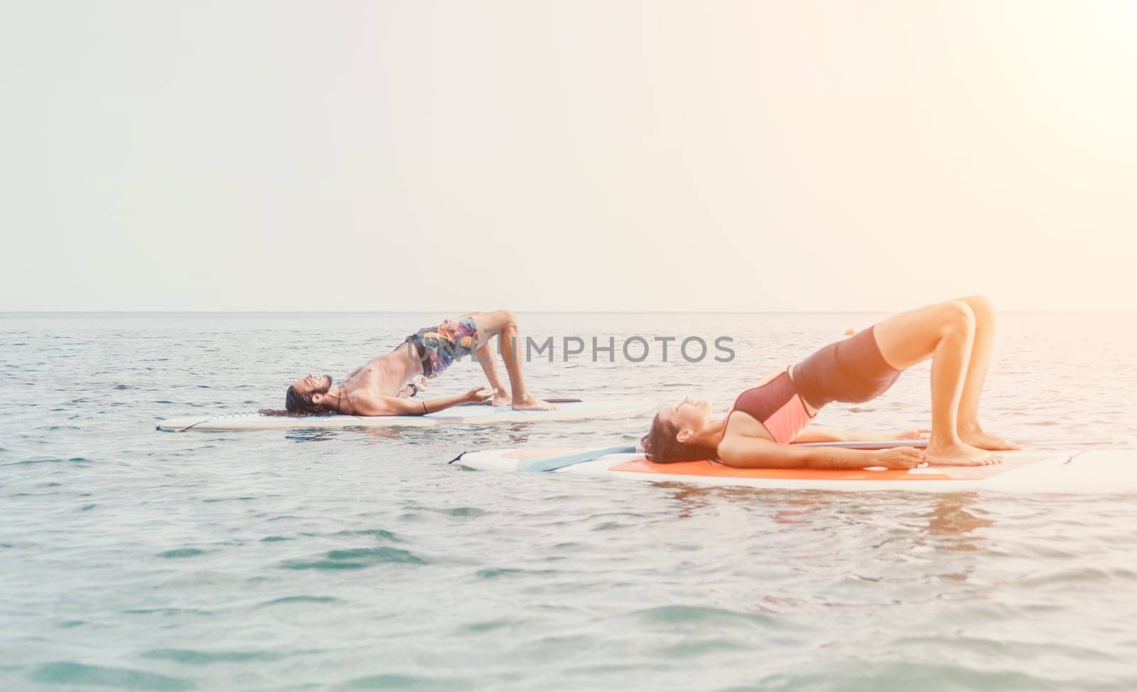 Woman sup yoga. Happy young sporty woman practising yoga pilates on paddle sup surfboard. Female stretching doing workout on sea water. Modern individual female outdoor summer sport activity