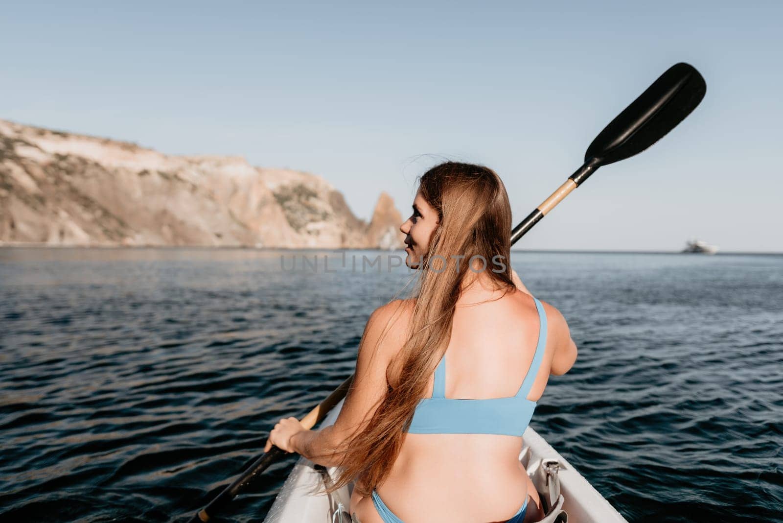 Woman in kayak back view. Happy young woman with long hair floating in kayak on calm sea. Summer holiday vacation and cheerful female people relaxing having fun on the boat. by panophotograph