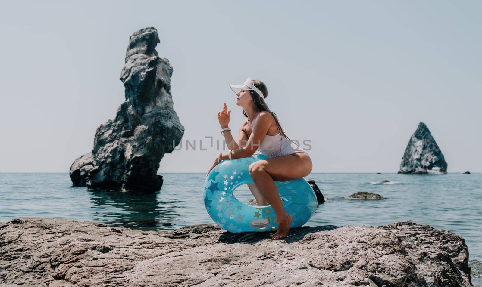 Woman summer sea. Happy woman swimming with inflatable donut on the beach in summer sunny day, surrounded by volcanic mountains. Summer vacation concept