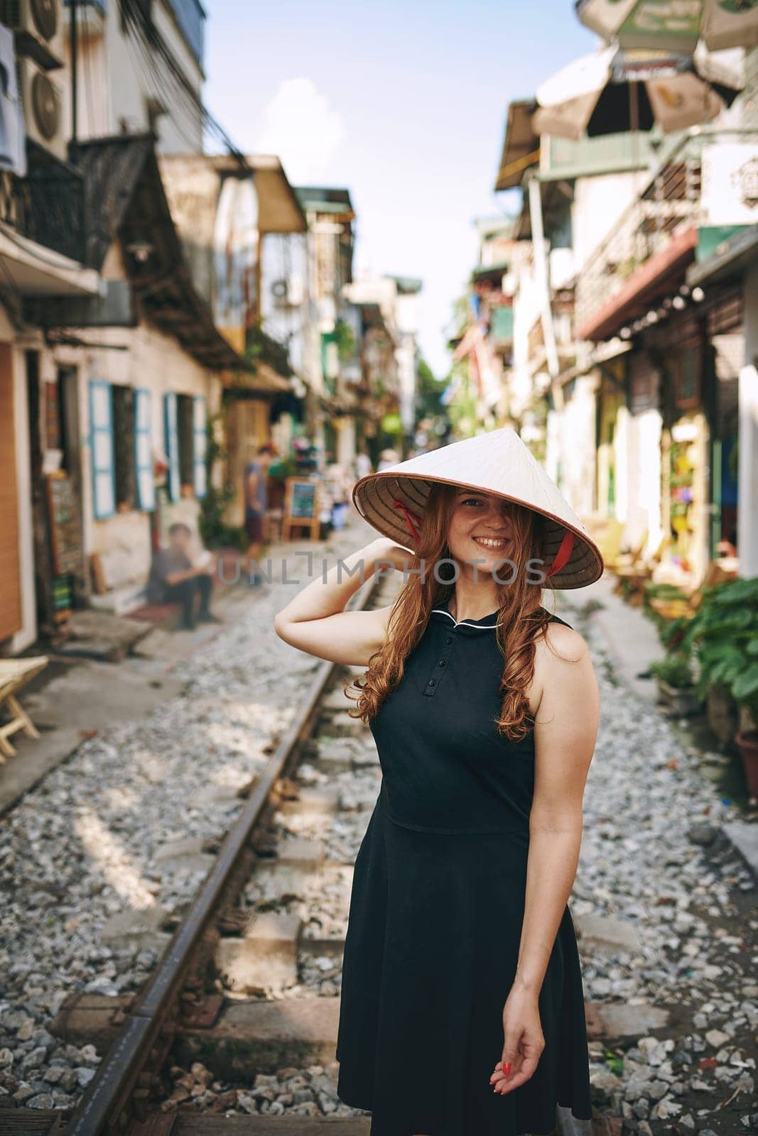 Travel to seek adventure and feel alive. a young woman wearing a conical hat while exploring a foreign city. by YuriArcurs