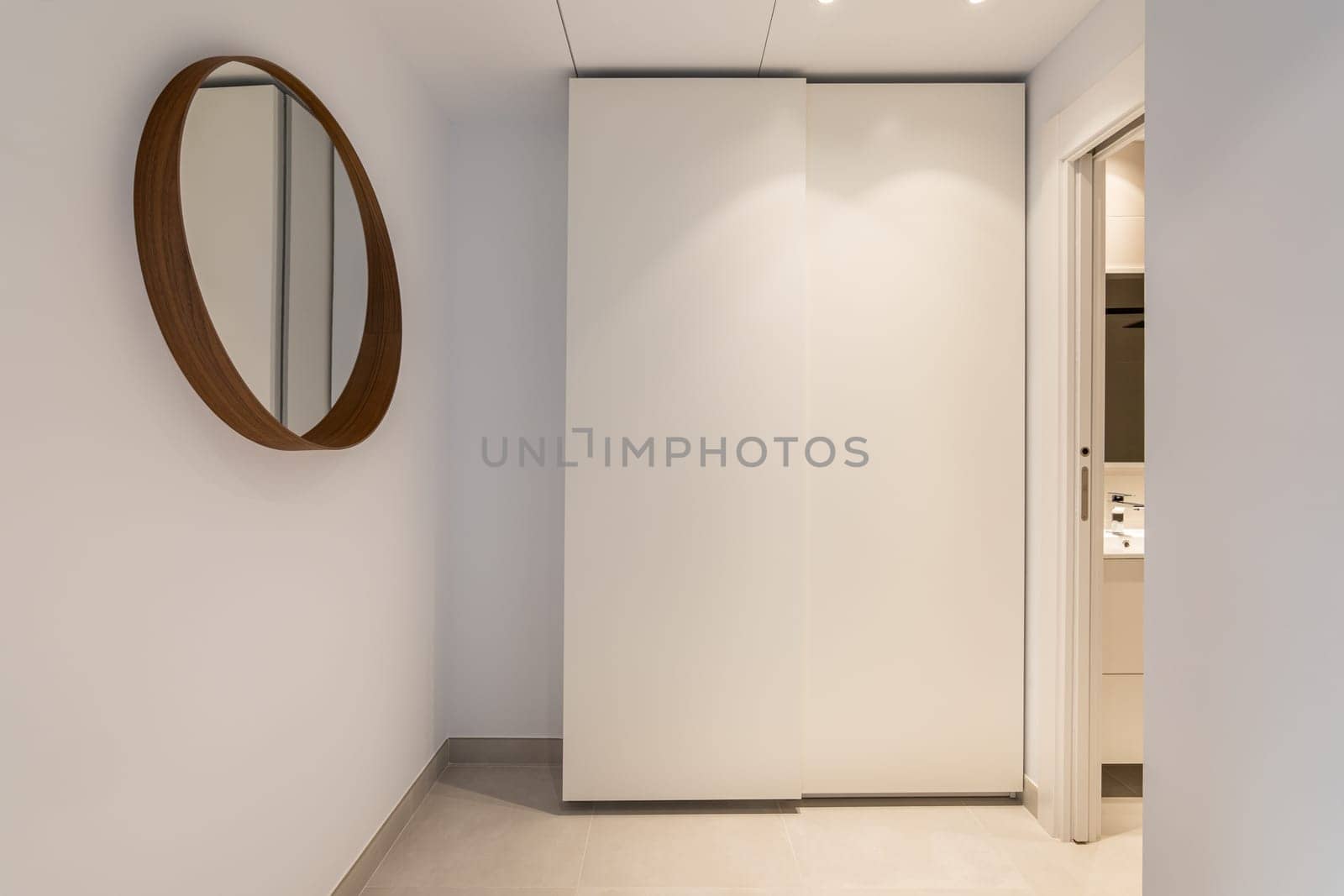 Comfortable corner in room with a mirror and a wardrobe with an entrance to the bathroom in light beige tones. Concept of comfortable layout in an apartment after renovation. Copyspace.