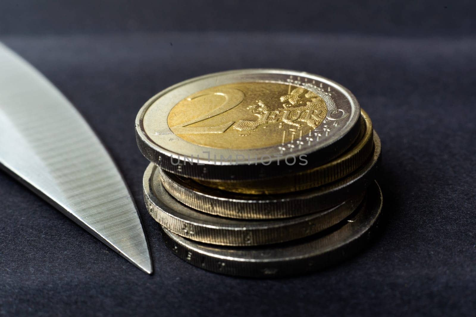 Knife blade placed on euro coin, calculator. Concept cutting rates, money business, crime. Macro. by Zelenin