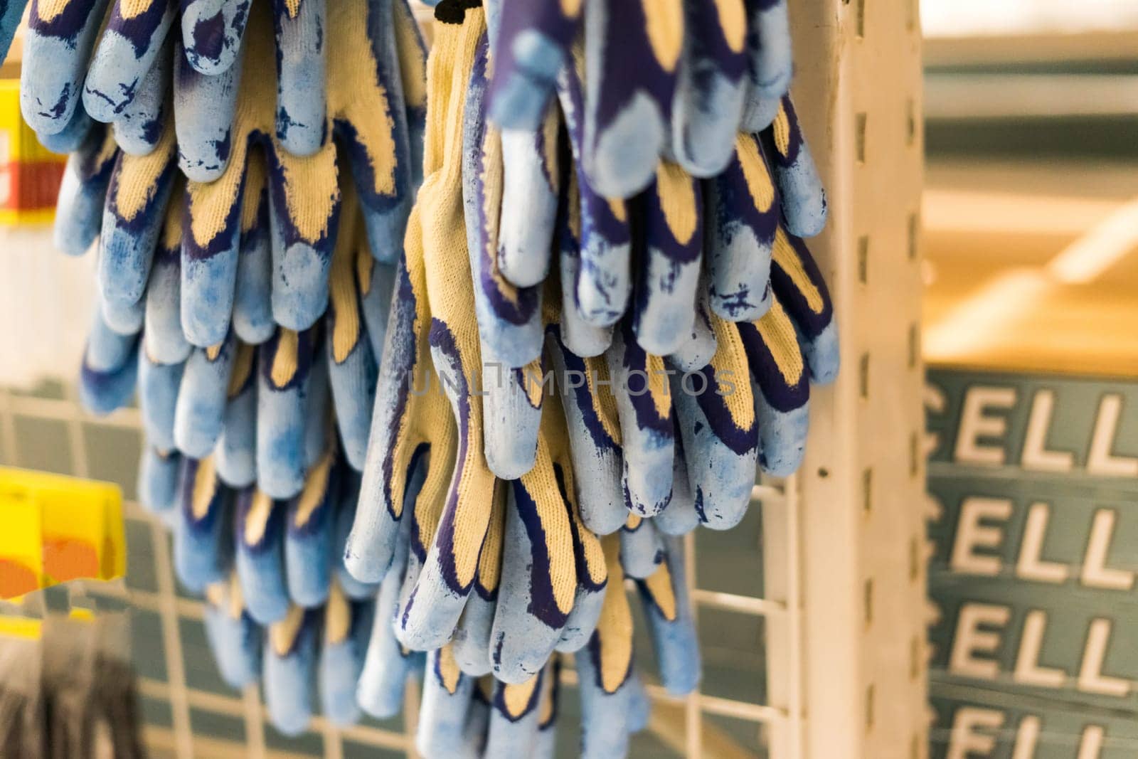 Rubberized grey work gloves hanging on the wall. Part of work-wear and protection equipment. by Zelenin