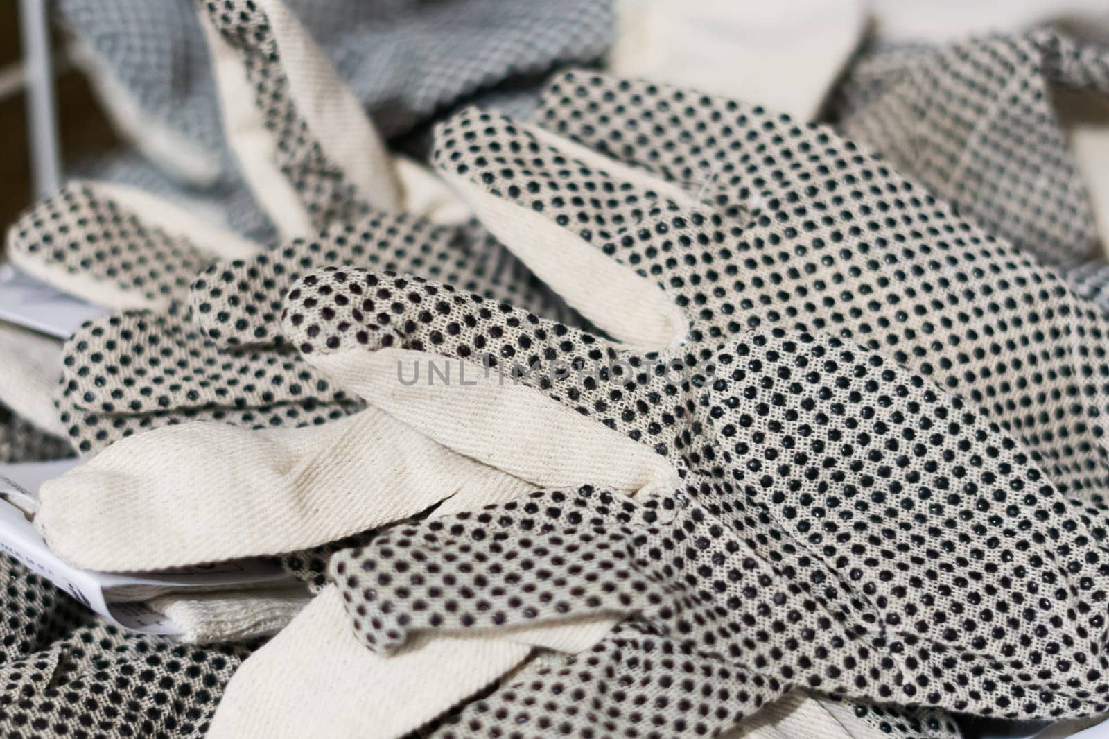 Rubberized grey work gloves hanging on the wall. Part of work-wear and protection equipment. by Zelenin