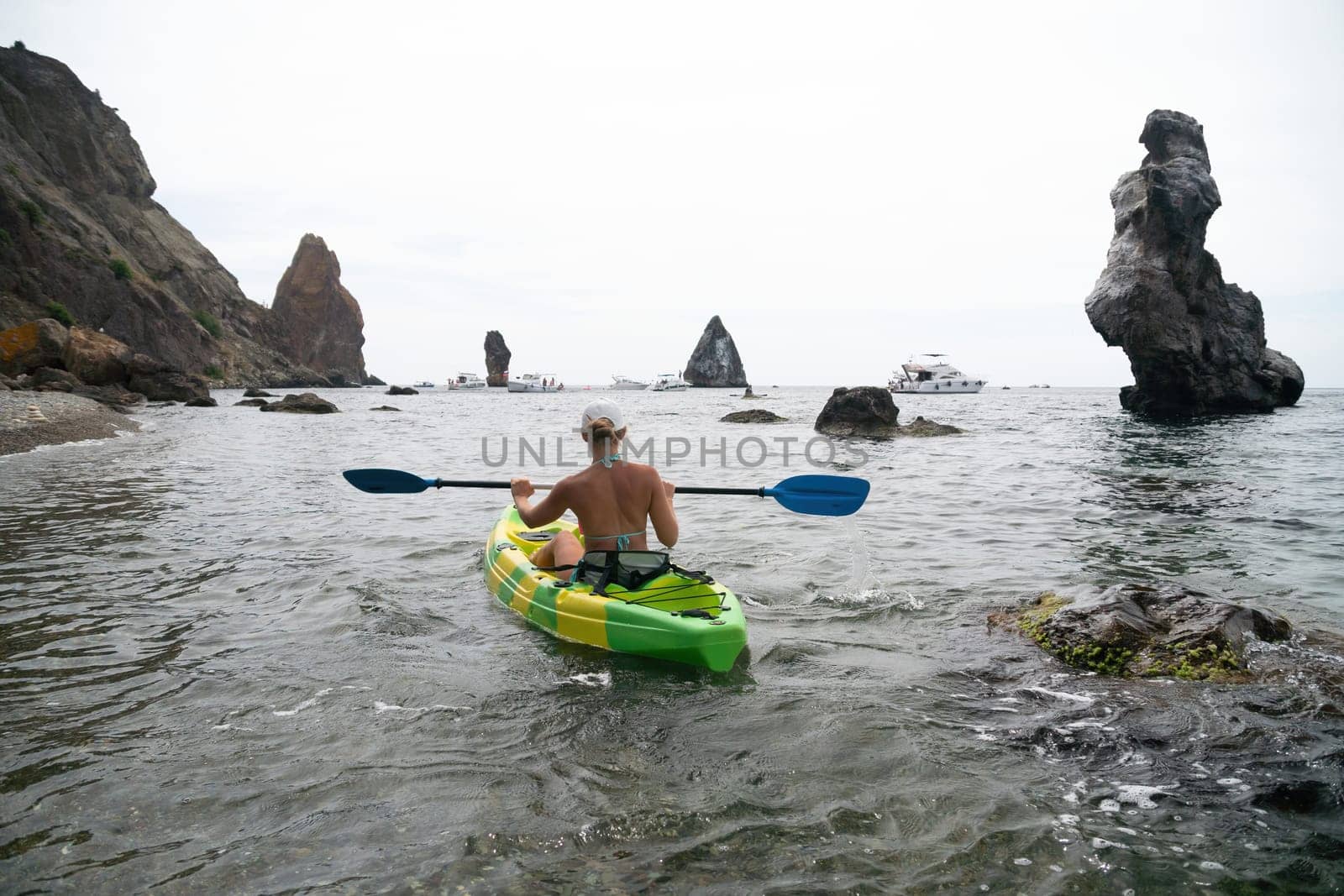 Woman kayak sea. Happy tourist takes sea photo in kayak canoe for memory. Woman traveler poses amidst volcanic mountains during adventurous journey in kayak. by panophotograph