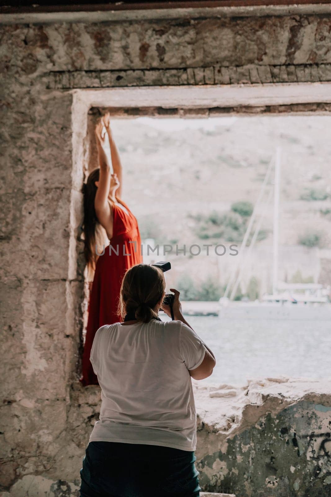 Woman travel portrait. Happy woman with long hair looking at camera and smiling. Close up portrait cute woman in a res long dress posing on backdrop of old travel city near sea by panophotograph