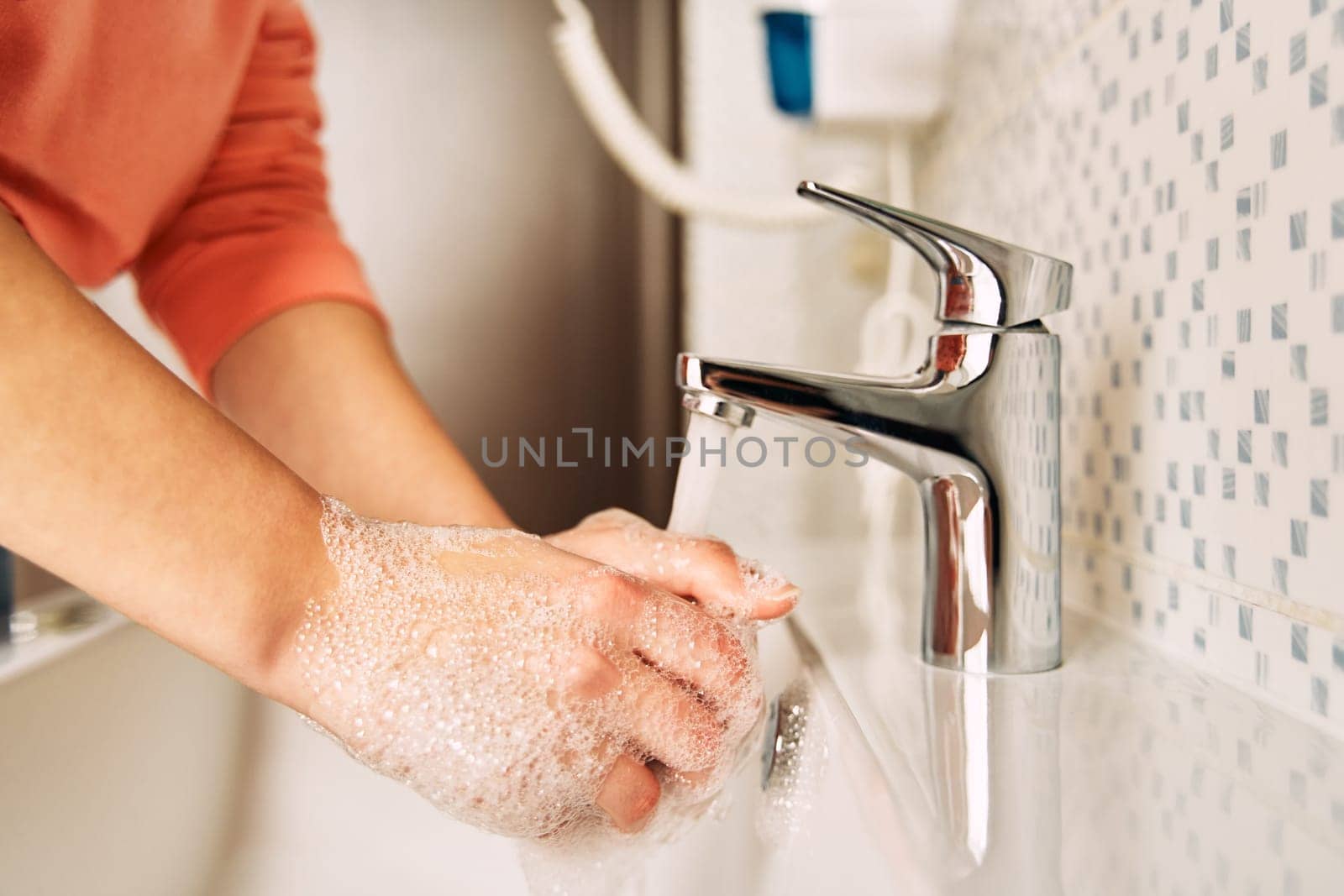 The young girl washes her hands with soap to prevent coronavirus. Hygiene to stop spreading coronavirus.