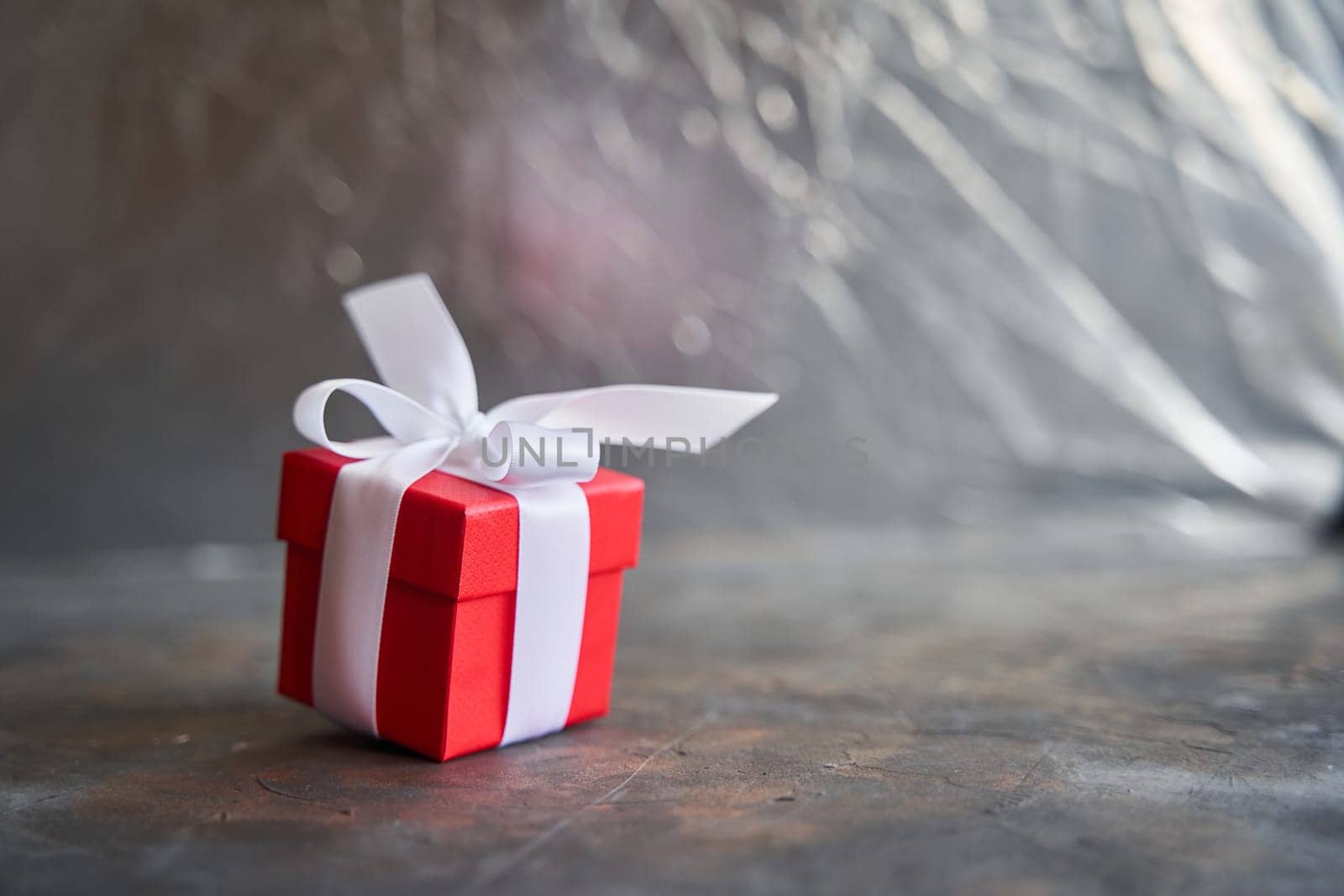 Small red gift box with white bow on dark background by driver-s