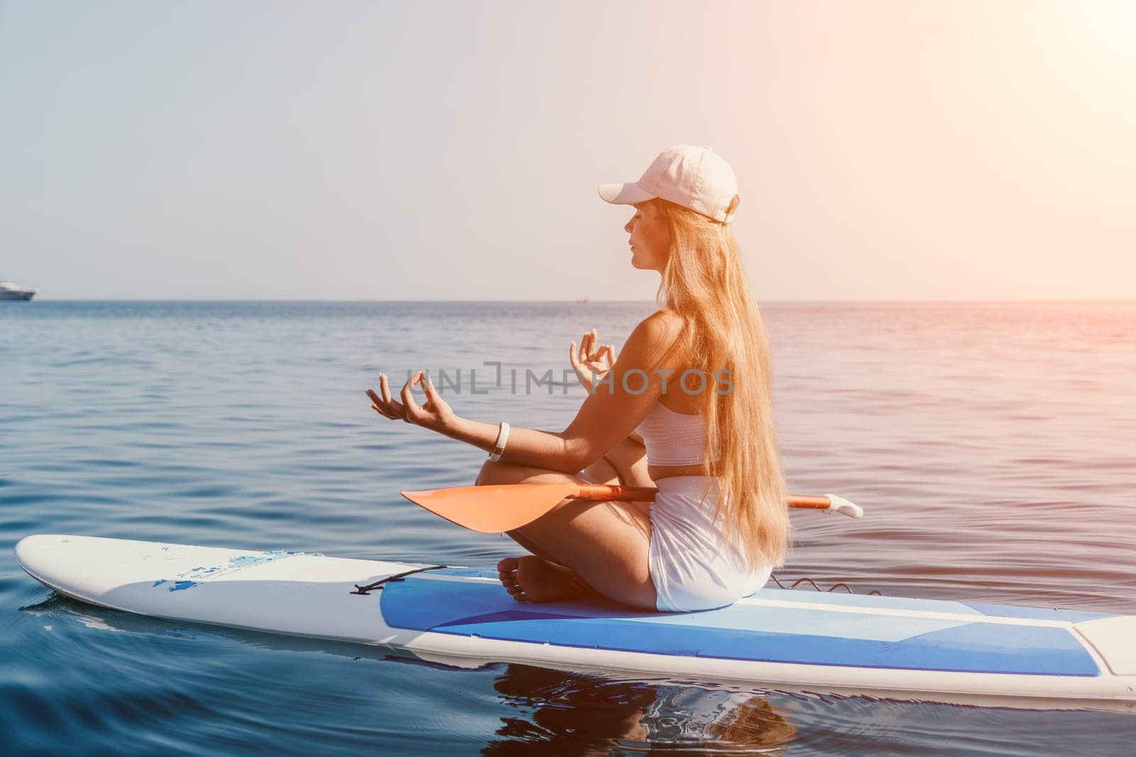 Close up shot of beautiful young caucasian woman with black hair and freckles looking at camera and smiling. Cute woman portrait in a pink bikini posing on a volcanic rock high above the sea