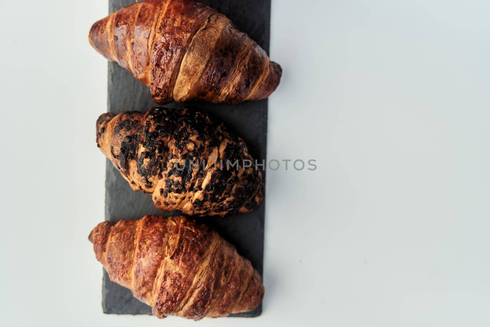 three croissants on a black tray top view by driver-s
