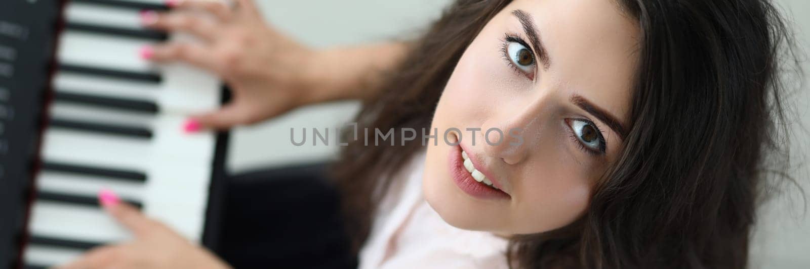 Portrait of happy woman looking up and playing synthesizer. Beautiful woman at music lesson concept