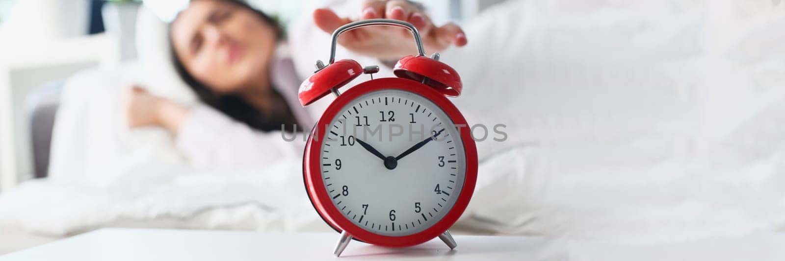 Dissatisfied woman turns off the alarm clock in bed by kuprevich