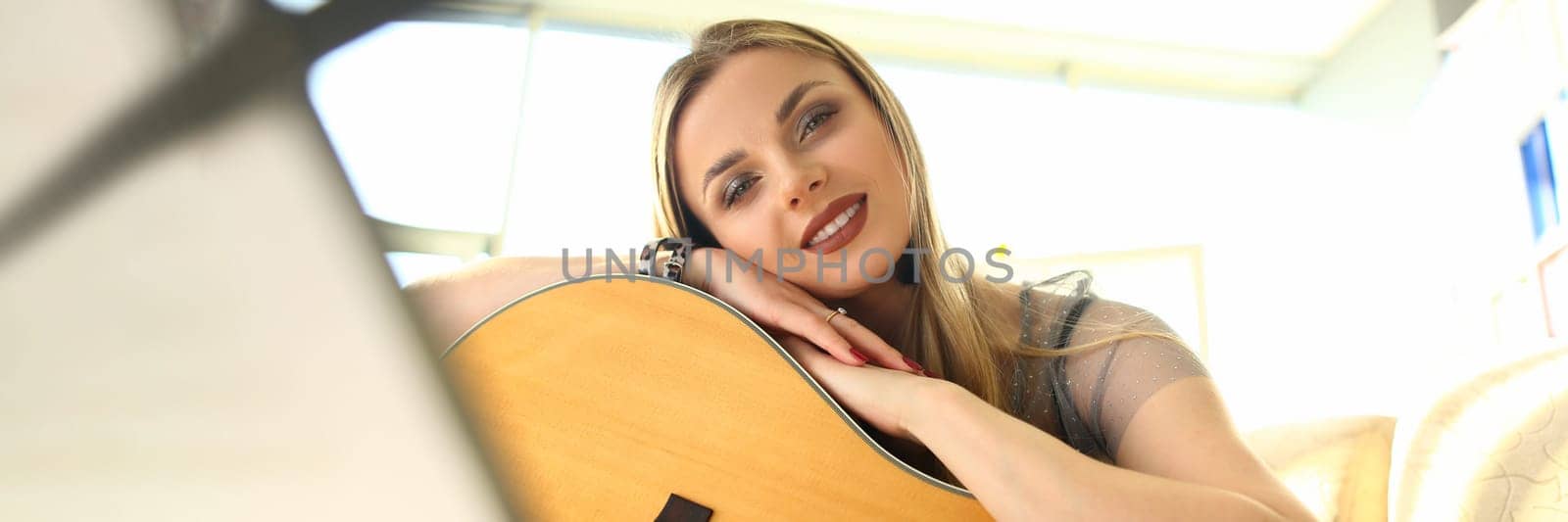 Young beautiful woman playing acoustic guitar at home. Learning to play guitar and music concept