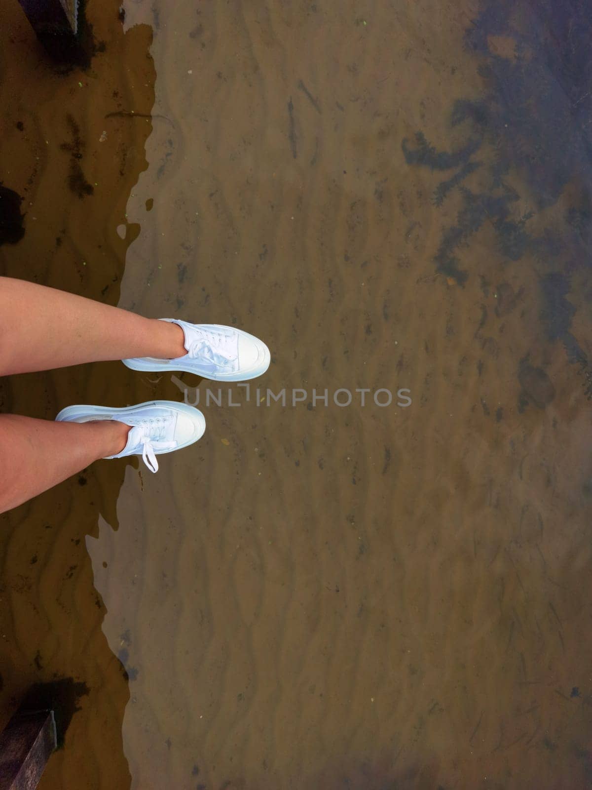 Woman legs above water on a dock, summer relax by sarymsakov