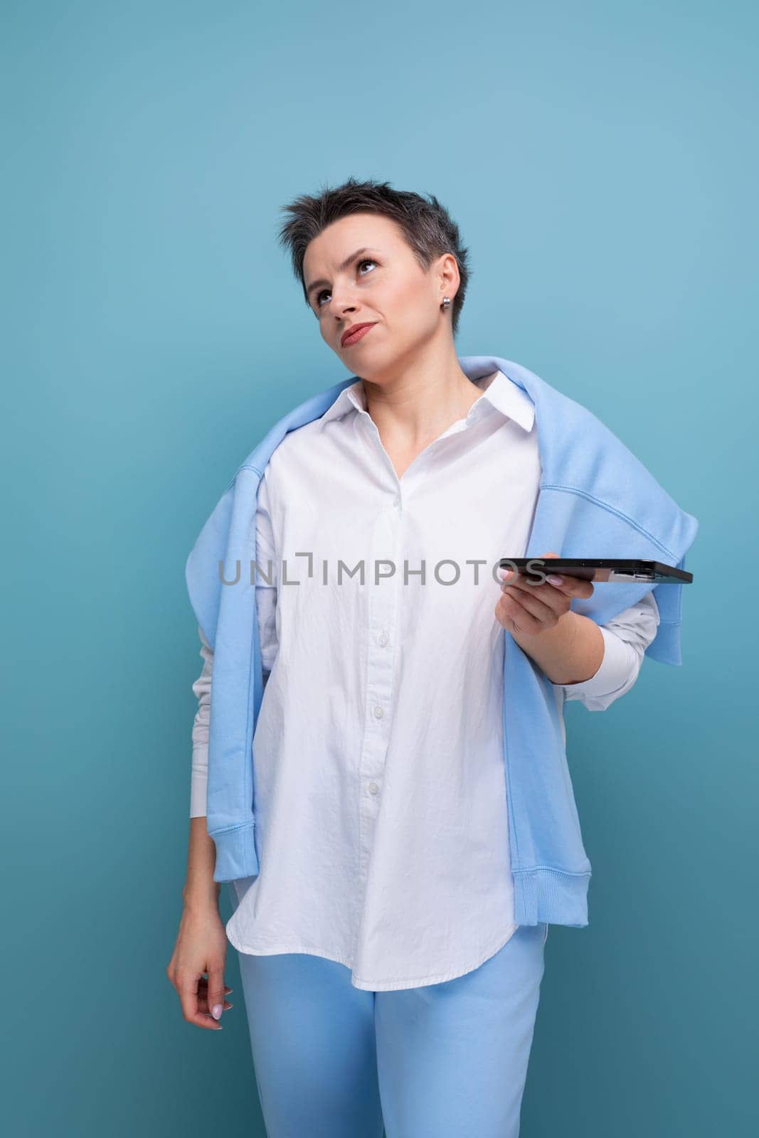 woman holding phone and looking up thoughtfully.