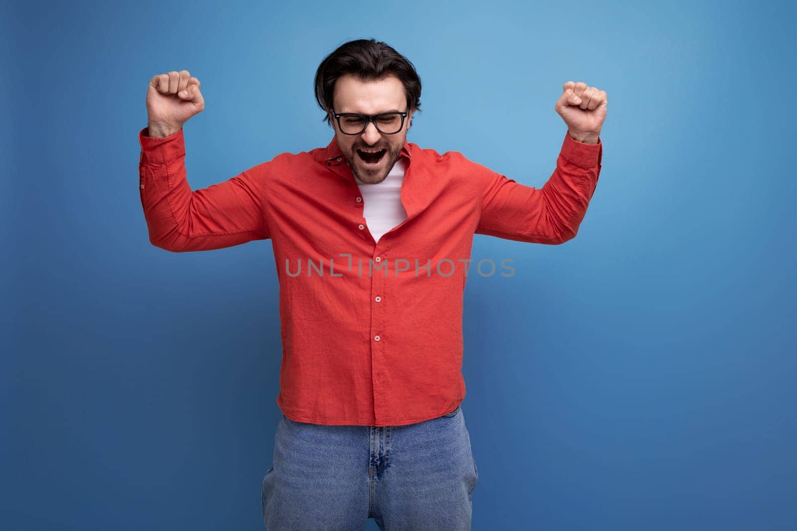 joyful 35 year old brunette millennial man with gorgeous hair in a red shirt.