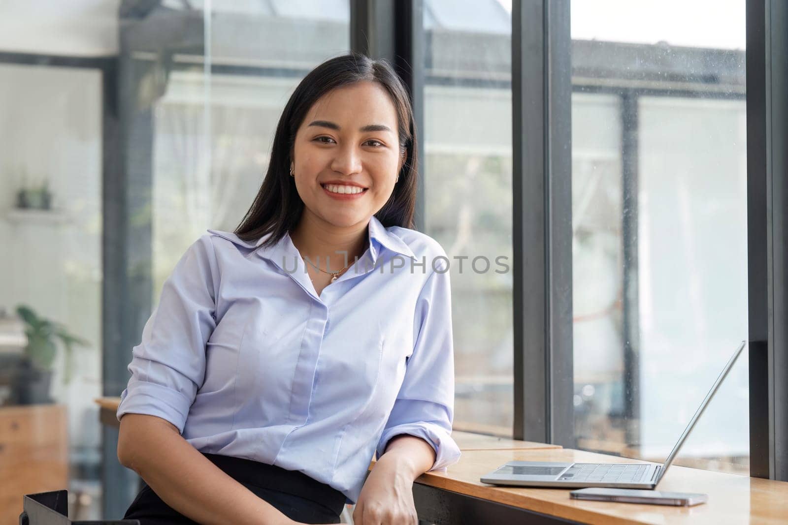 Portrait of businesswoman in modern office looking smiling at camera. Confident business woman in office.