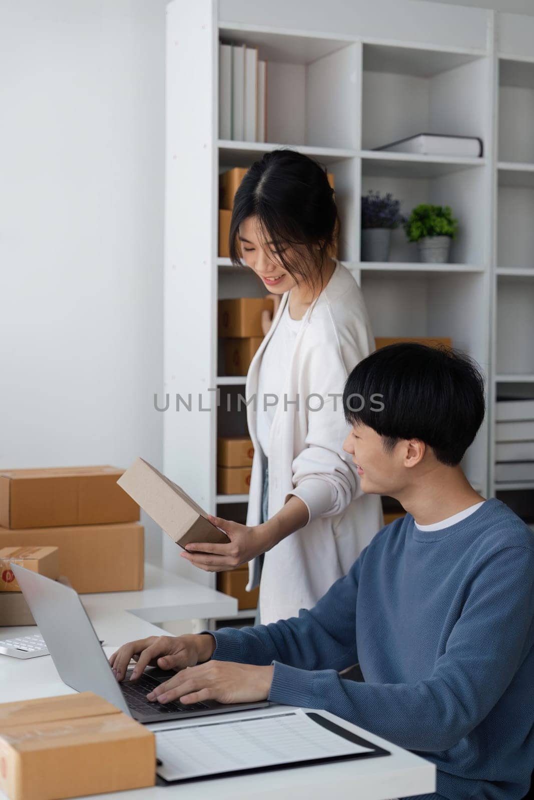 Couple startup small business working with laptop at workplace. freelance man and woman seller check product order, packing goods for delivery to customer. Online selling, e-commerce.