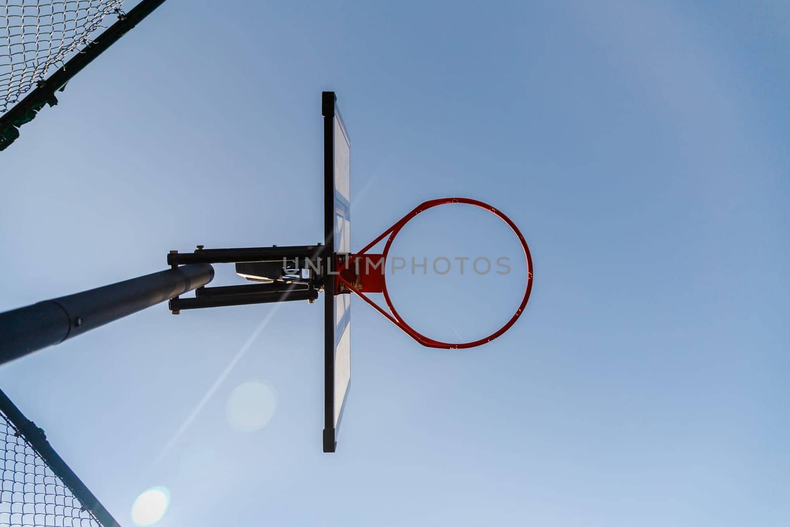 Bottom view of a basketball hoop outdoor. Blue sky as background and copy space. Urban street sport game.