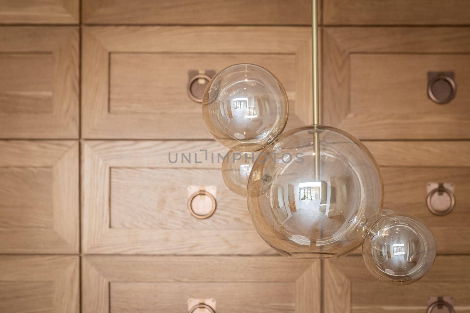 modern glass lamp chandelier close-up on the background of a wooden decorative wall.
