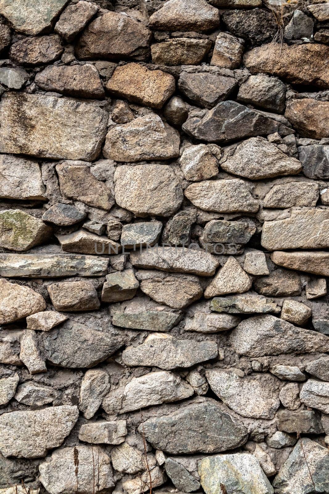 Medieval grunge vertical background of natural stones bonded with cement mortar.