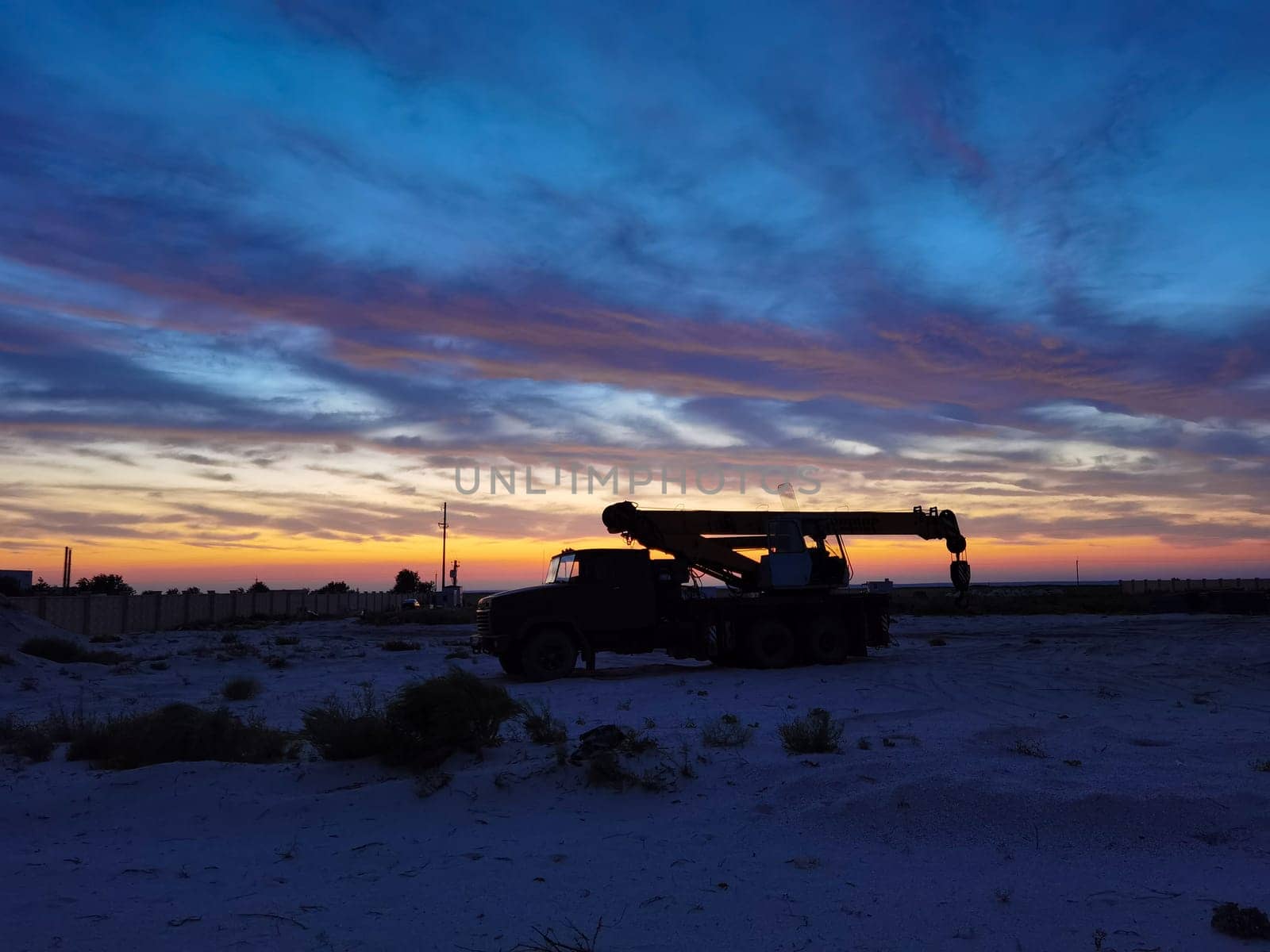 Silhouette of a Boom truck in the oilfield at sunset.