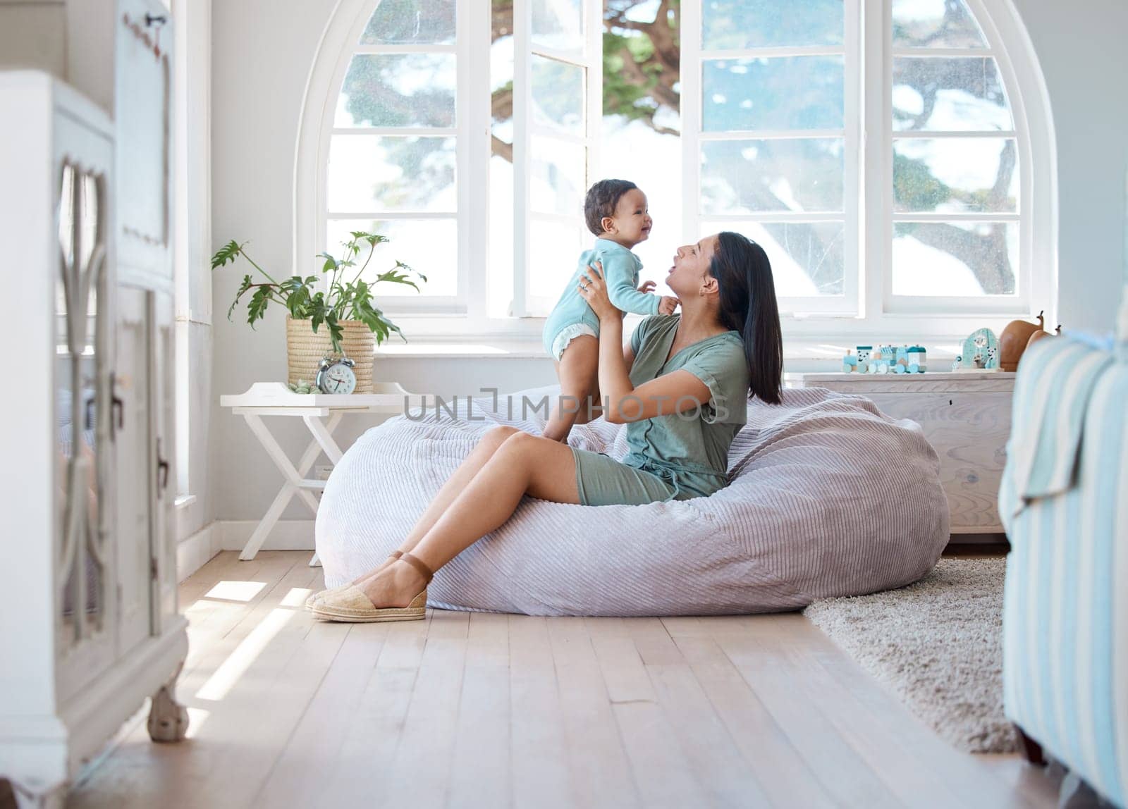 Home, mother and holding baby to relax on bean bag for love, care and quality time together in childhood development. Mom, infant and carrying newborn kid in living room for support, fun and comfort.