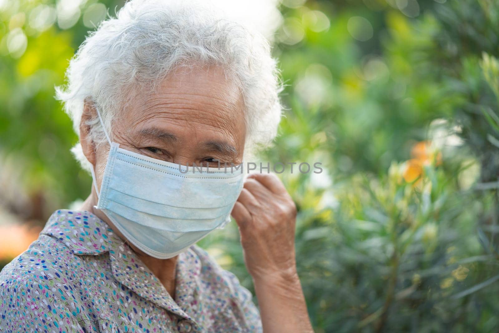 Asian elderly woman with face mask, fresh and happy in morning at park.