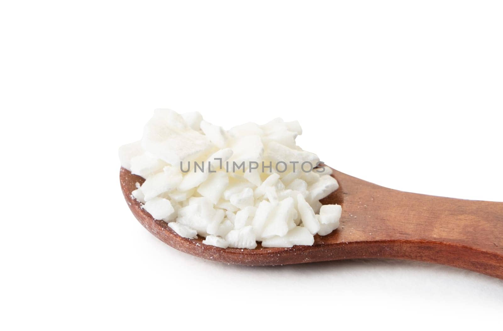 Organic white soy wax flakes for candles in small measure spoon isolated on white background with shadow