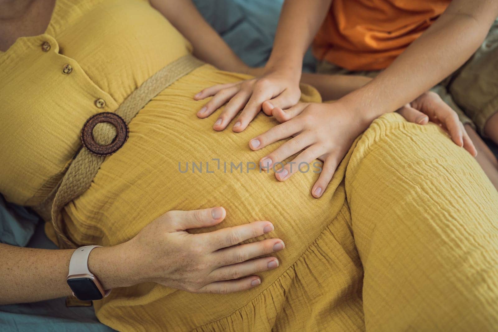 Young pregnant mother hugging her little boy lying in bed at night. Caring and loving parent hugging child.