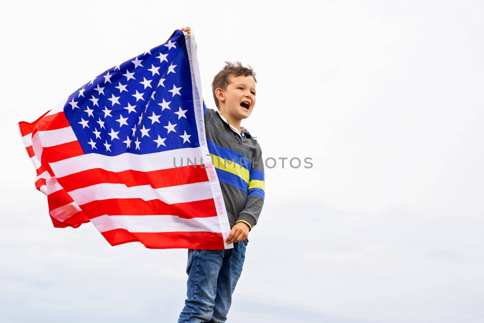 Emotional portrait of patriotic american boy holding USA flag waving in the wind by andreyz