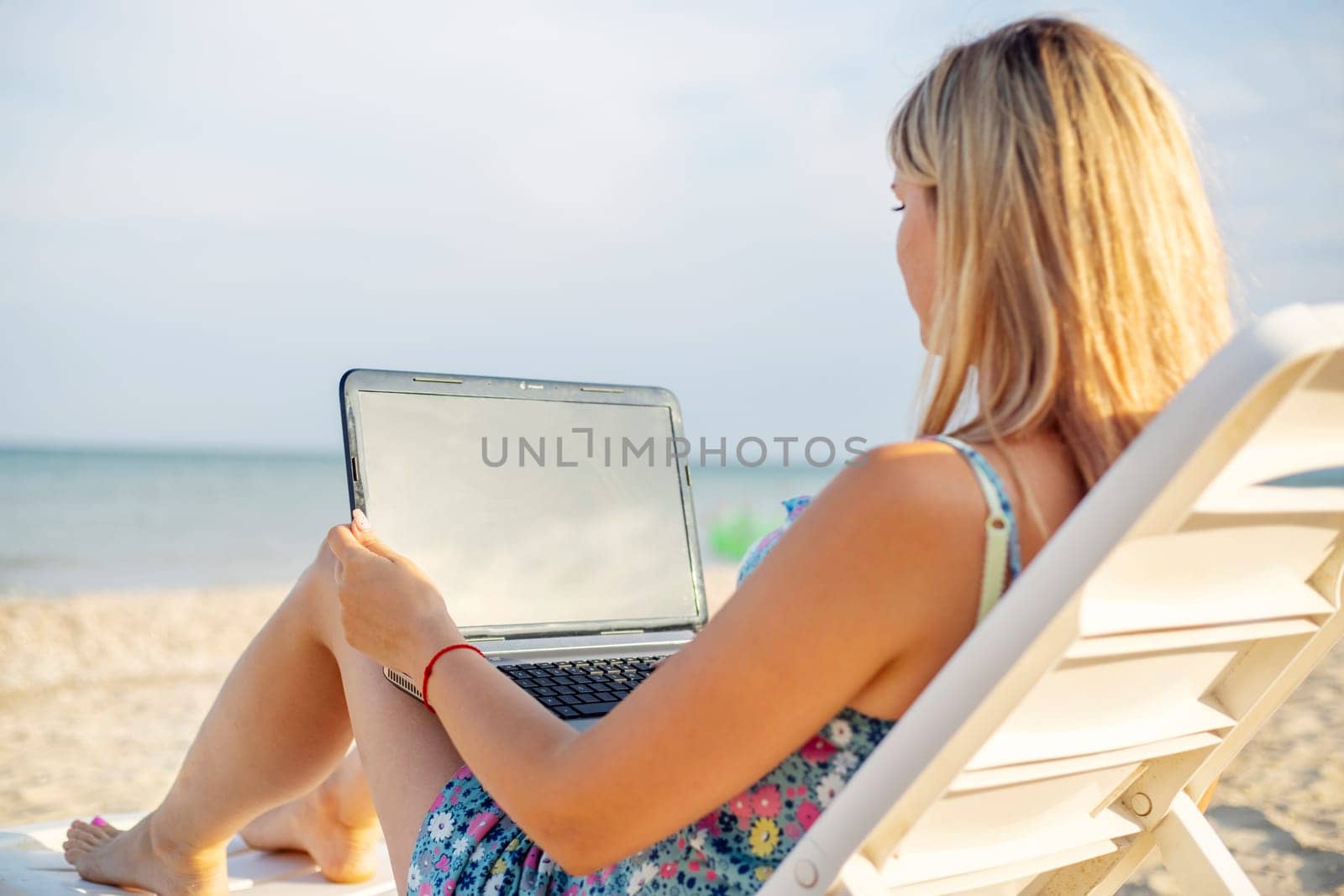 Beautiful young woman working with laptop on the tropical beach. Successful person concept.