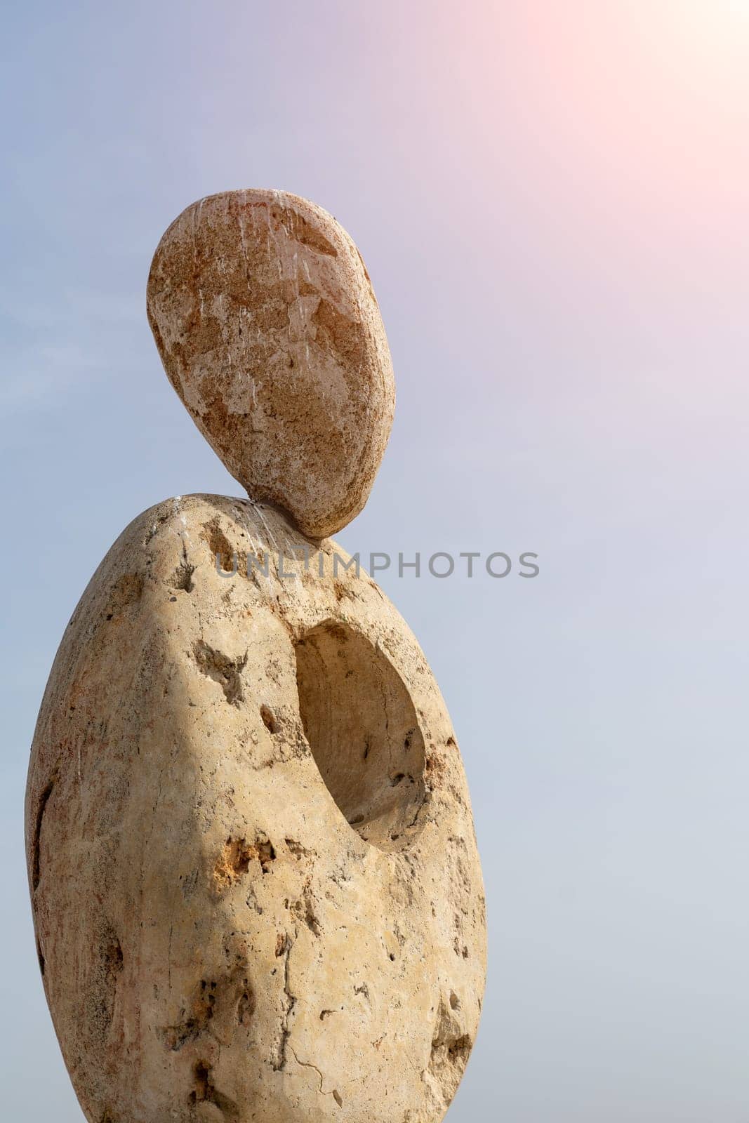 Sculpture symbol made of large pebbles against the blue sky by Matiunina