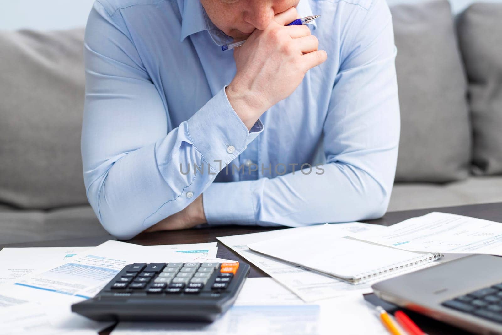 Distressed young man sit at desk paying bills feel stressed having financial problems. Unhappy upset male frustrated by debt or bankruptcy managing household budget or expenses.